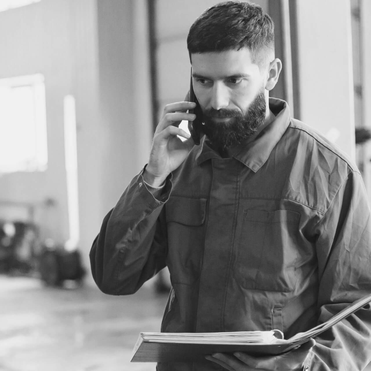 Instalador al teléfono sosteniendo un manual en papel con expresión preocupada.